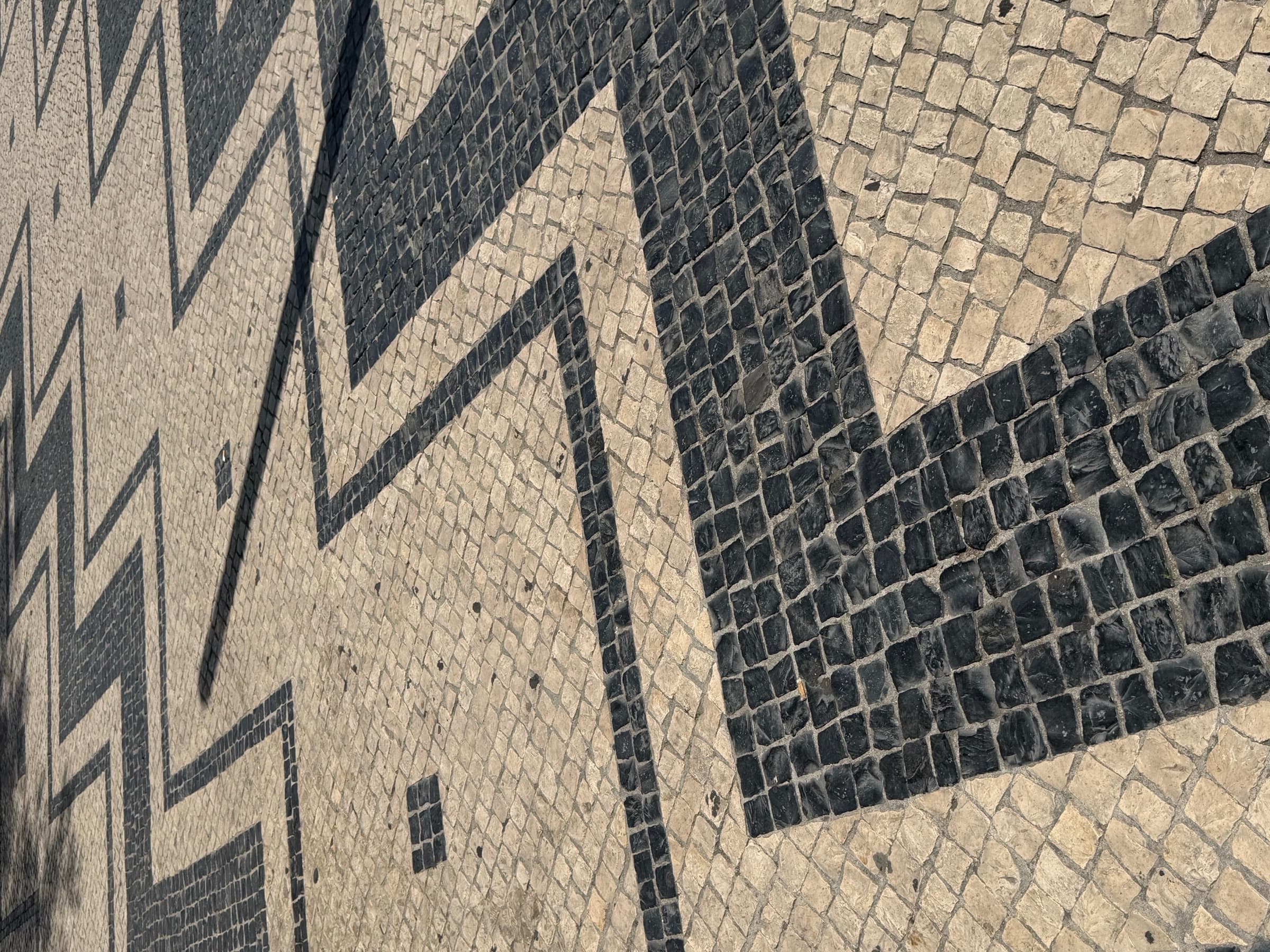 Black-and-white calçada portuguesa — Lisbon's mosaic pavement, zigzag chevrons cut in stone