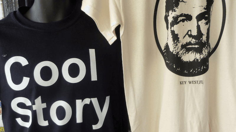 A 'Cool Story' t-shirt hanging beside a Hemingway 'Key West' t-shirt